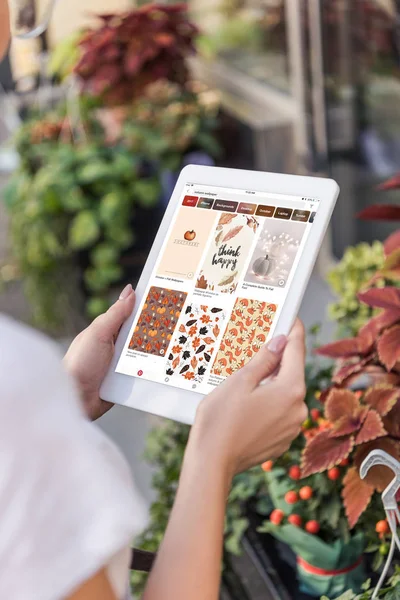 Cropped image of florist using tablet with loaded pinterest page near flower shop — Stock Photo