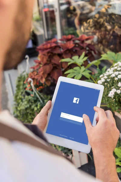 Abgeschnittenes Bild eines Blumenhändlers mit Tablet mit geladener Facebook-Seite in der Nähe eines Blumengeschäfts — Stockfoto