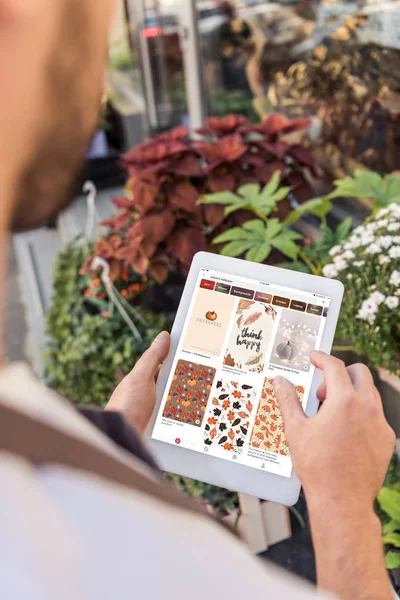 Immagine ritagliata di fiorista utilizzando tablet con pagina caricata pinterest vicino al negozio di fiori — Foto stock