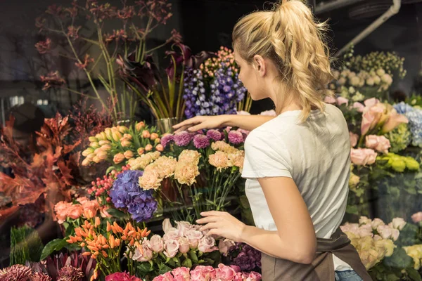 Вид ззаду флориста, який піклується про букети в квітковому магазині — стокове фото