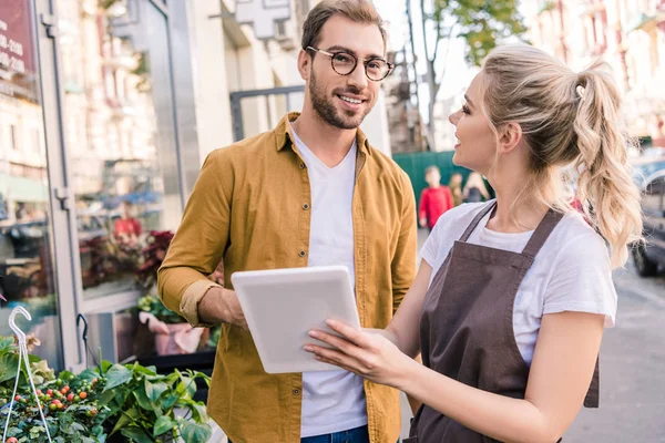 Fleuriste et client souriant utilisant une tablette au magasin de fleurs — Photo de stock