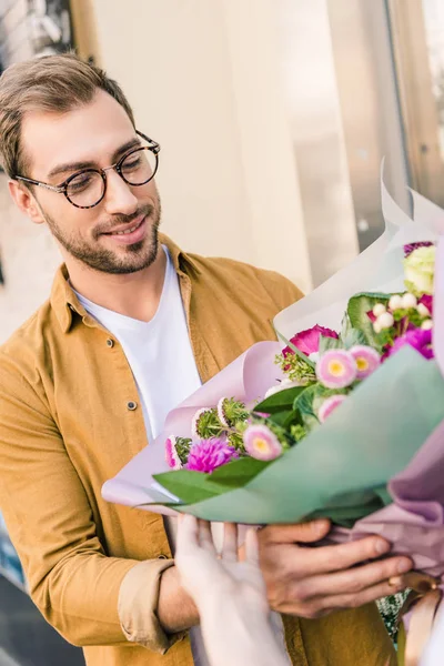 Florist giving beautiful bouquet of chrysanthemums to handsome customer near flower shop — Stock Photo