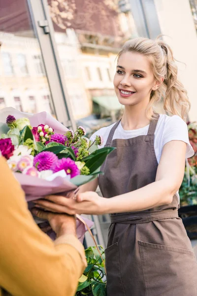 Lächelnd attraktive Floristin gibt schönen Strauß Chrysanthemen an Kunden in der Nähe Blumenladen — Stockfoto