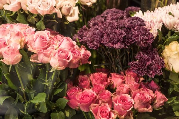 Schöne rosa und weinrote Rosen und Nelkenblüten im Blumenladen — Stockfoto