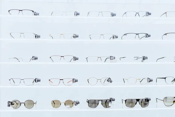 Білі полиці зі стильними окулярами та сонцезахисними окулярами в офтальмологічному магазині — стокове фото