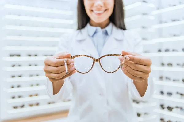 Vista recortada del optometrista profesional que sostiene las gafas graduadas - foto de stock