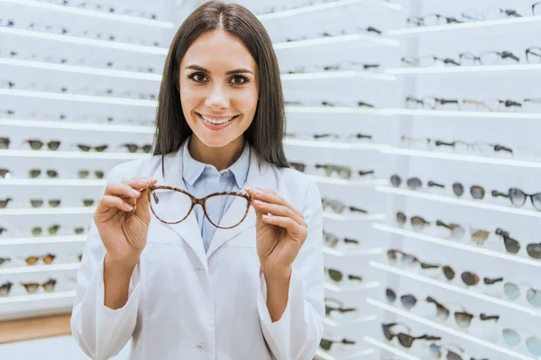 Professioneller lächelnder Augenoptiker mit Brille im Augengeschäft — Stockfoto