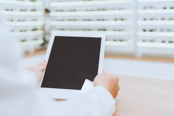 Visão parcial do óptico usando tablet digital com tela em branco no trabalho em óptica — Fotografia de Stock