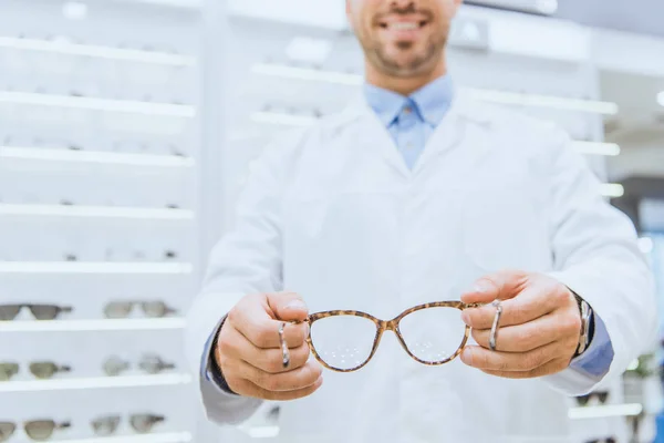 Vista recortada del optometrista que sostiene las gafas, enfoque selectivo - foto de stock