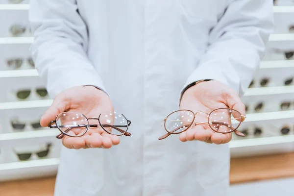 Cropped view of doctor in white coat holding eyeglasses — Stock Photo