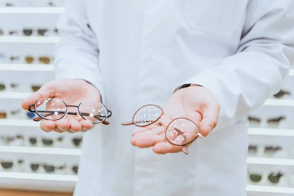 Partial view of professional doctor in white coat holding glasses — Stock Photo