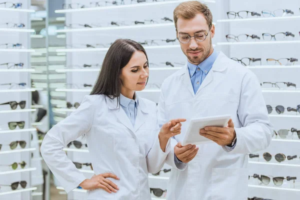 Dois optometristas trabalhando e usando tablet digital em óptica — Fotografia de Stock