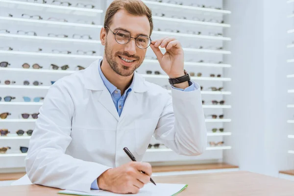 Arzt im weißen Kittel schreibt Diagnose in Optik — Stockfoto