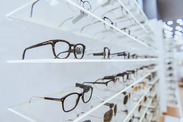 Selective focus of white shelves with stylish glasses in ophthalmology — Stock Photo