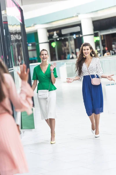 Selective focus of cheerful stylish girls meeting each other in shopping mall — Stock Photo