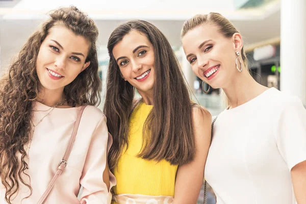 Beautiful happy young women smiling at camera in shopping mall — Stock Photo