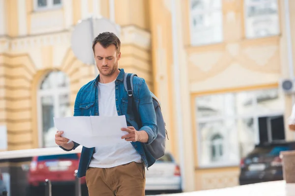 Portrait of focused traveler with backpack and map on city street — Stock Photo