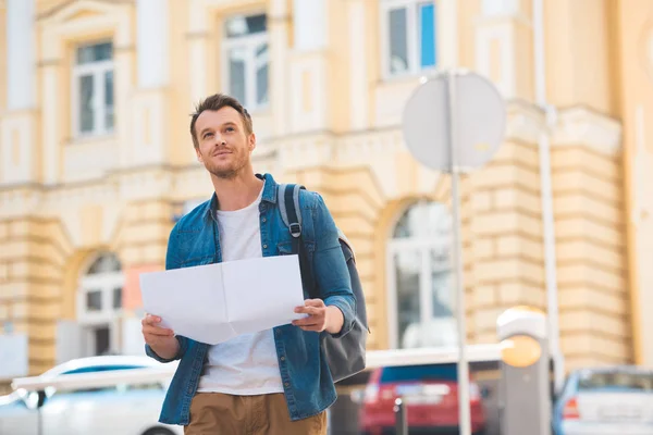Portrait of smiling traveler with backpack and map on city street — Stock Photo
