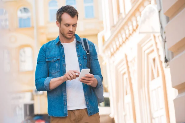 Ritratto di uomo concentrato in camicia di denim con smartphone su strada — Foto stock