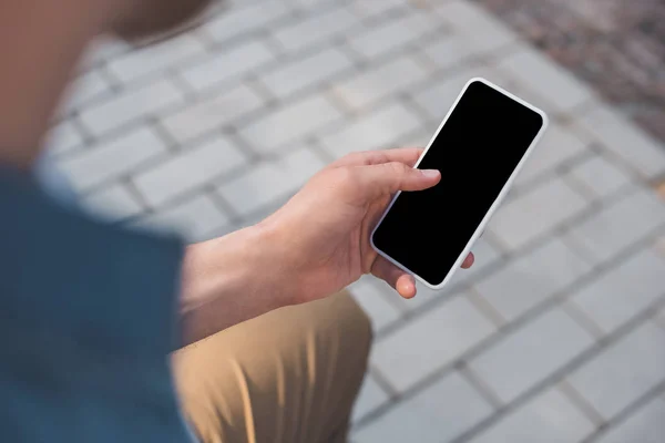 Обрезанный снимок человека с помощью смартфона с пустым экраном на улице — стоковое фото