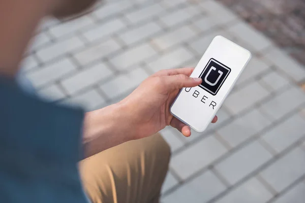 Cropped shot of man using smartphone with uber app on screen — Stock Photo