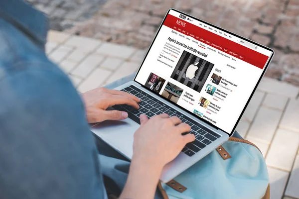 Cropped shot of man using laptop with bbc website on street — Stock Photo