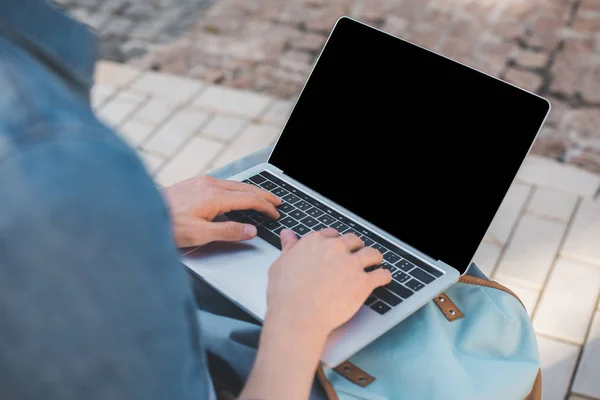 Cropped shot of man using laptop with blank screen on street — Stock Photo