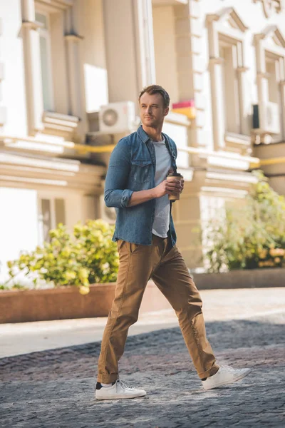 Attrayant jeune homme avec du café pour aller marcher par la ville — Photo de stock