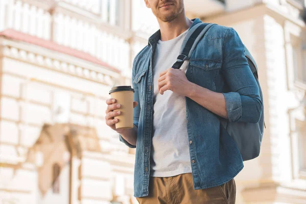 Tiro cortado de jovem com café para ir e mochila andando na rua — Fotografia de Stock