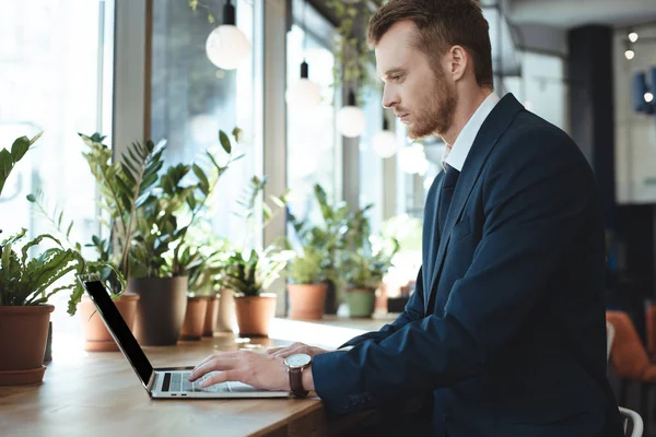 Seitenansicht des fokussierten Geschäftsmannes mit Laptop am Tisch im Café — Stockfoto