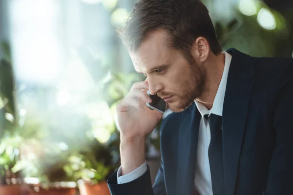 Seitenansicht eines konzentrierten Geschäftsmannes, der im Coffeeshop auf dem Smartphone spricht — Stockfoto