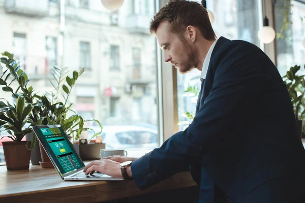 Vista lateral do remoto empresário concentrado trabalhando no laptop à mesa com xícara de café no restaurante — Fotografia de Stock