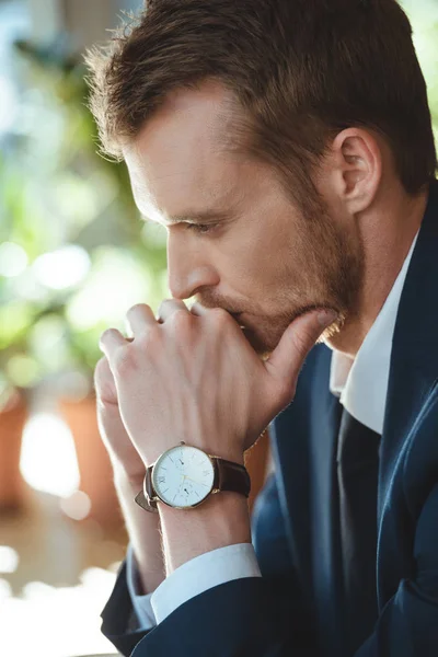 Vista lateral del hombre de negocios reflexivo con reloj en la muñeca en la cafetería - foto de stock