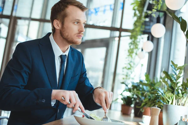 Seitenansicht eines nachdenklichen Geschäftsmannes im Anzug, der beim Mittagessen im Café wegschaut — Stockfoto