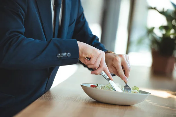 Vista parcial del hombre de negocios en la mesa con almuerzo servido en el restaurante - foto de stock