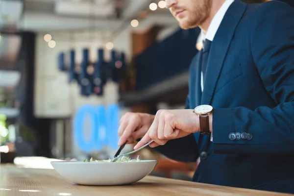 Vista parcial del hombre de negocios en la mesa con almuerzo servido en el restaurante - foto de stock