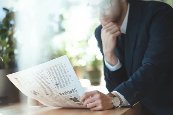 Vista parziale di uomo d'affari in occhiali che legge il giornale durante in caffè — Foto stock