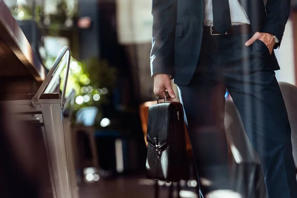 Обрезанный снимок бизнесмена с чемоданом в ресторане — стоковое фото