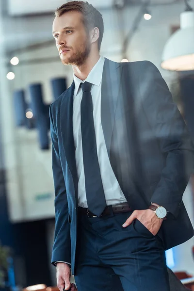 Hombre de negocios en traje elegante con la mano en el bolsillo de pie en la cafetería - foto de stock