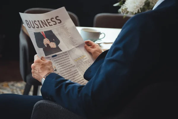 Vista parcial del empresario con periódico durante la pausa para el café en la cafetería - foto de stock