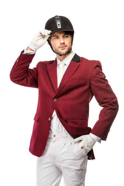 Guapo jinete joven en uniforme y casco mirando hacia otro lado aislado en blanco — Stock Photo