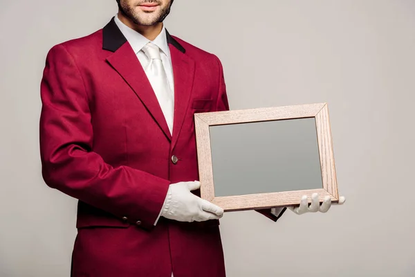 Tiro cortado de jovem cavaleiro em uniforme segurando quadro branco isolado em cinza — Fotografia de Stock