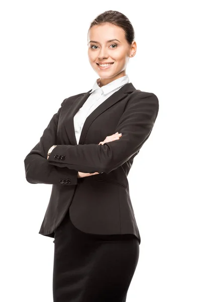 Heureuse jeune femme d'affaires en costume regardant caméra avec les bras croisés isolé sur blanc — Photo de stock