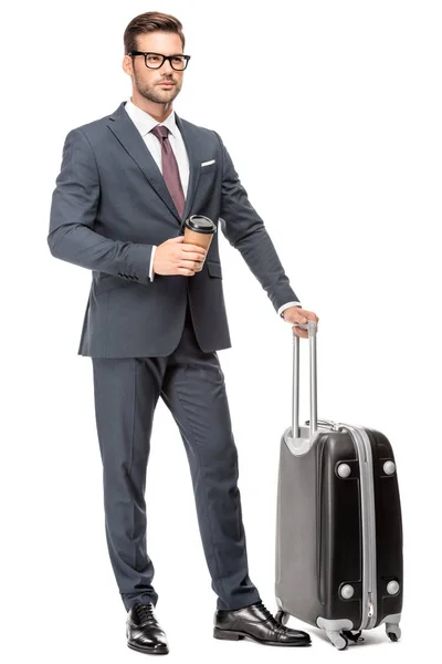 Beau jeune homme d'affaires avec des bagages et une tasse de café en papier regardant loin isolé sur blanc — Photo de stock
