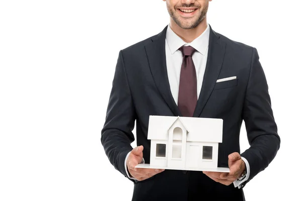 Partial view of young male architect in formal suit showing miniature house isolated on white — Stock Photo