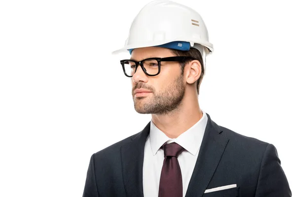 Confiado joven arquitecto masculino en gafas graduadas y sombrero duro mirando hacia otro lado aislado en blanco - foto de stock