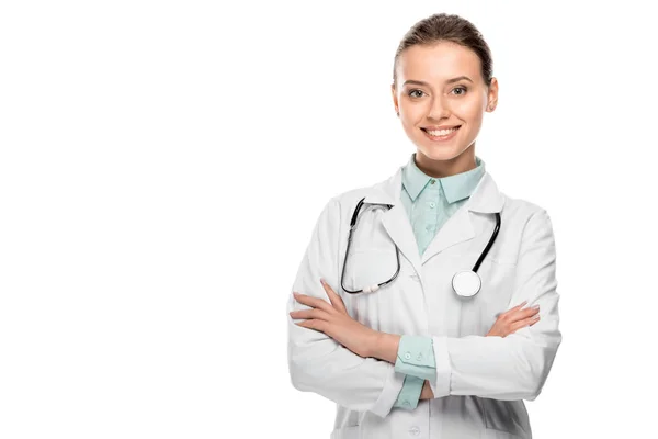 Happy beautiful female doctor in medical coat standing with crossed arms isolated on white — Stock Photo