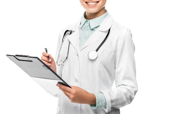 Vista parcial de la doctora en la escritura de la capa médica en el portapapeles aislado en blanco — Stock Photo