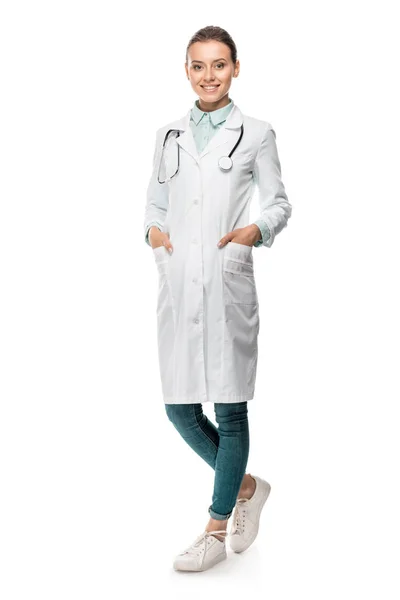 Happy young female doctor in medical coat with stethoscope over neck isolated on white — Stock Photo