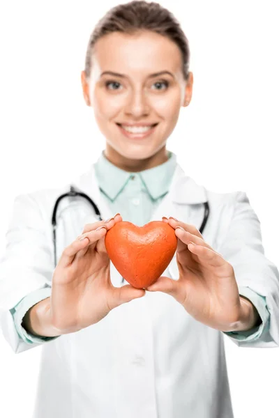 Smiling young female doctor with stethoscope over neck showing heart symbol isolated on white — Stock Photo